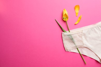 Photo of Yellow tulip and panties on pink background, top view with space for text. Menopause concept