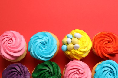 Photo of Delicious cupcakes with bright cream on red background, flat lay. Space for text