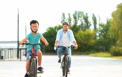 Photo of Dad and son riding bicycles together outdoors