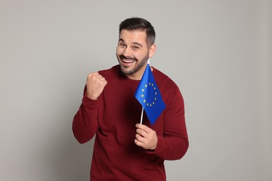 Man with flag of European Union on light grey background