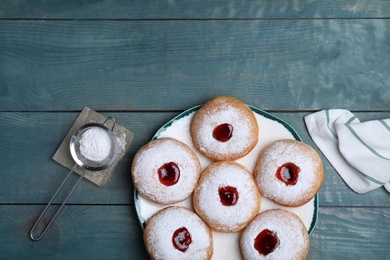 Photo of Hanukkah doughnuts with jelly and sugar powder served on blue wooden table, flat lay