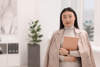 Portrait of beautiful businesswoman with tablet in office. Space for text