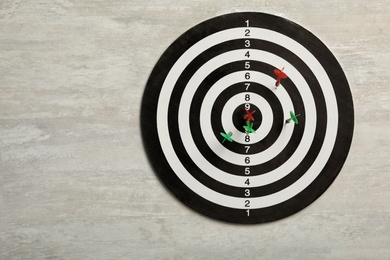 Dart board with color arrows on light stone background, top view. Space for text