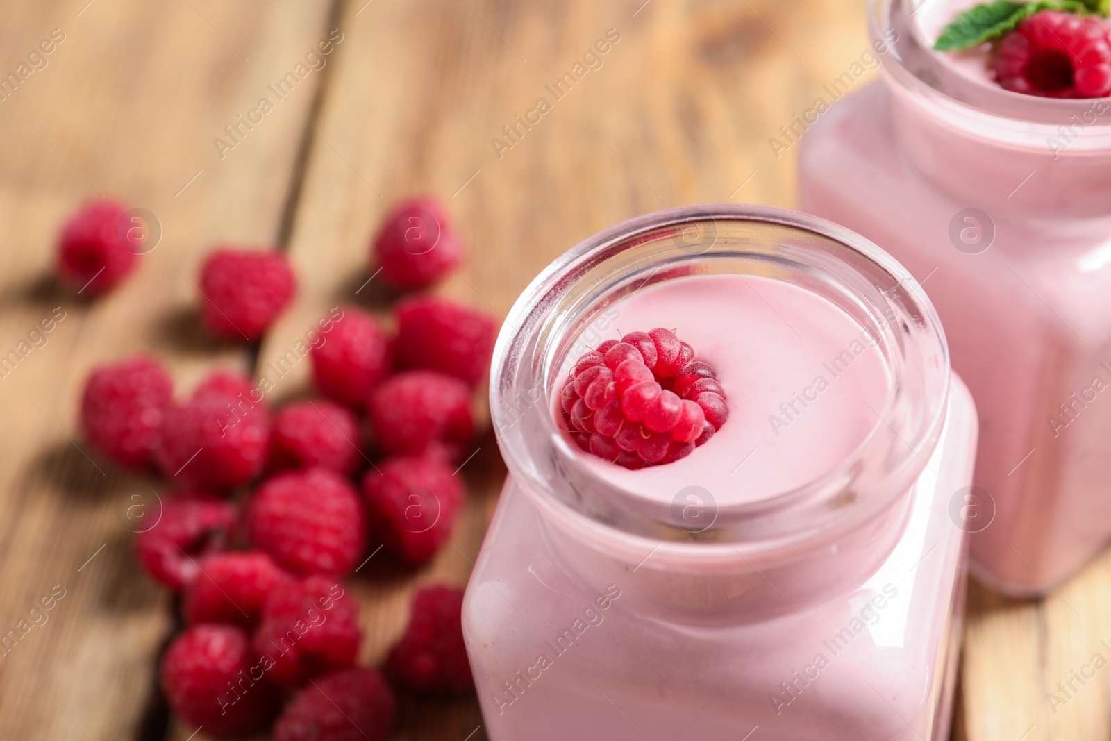 Photo of Glass jar of tasty smoothie with raspberries on wooden table, closeup. Space for text