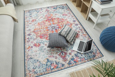 Stylish living room with beautiful carpet, laptop and pillows on floor, above view. Interior design