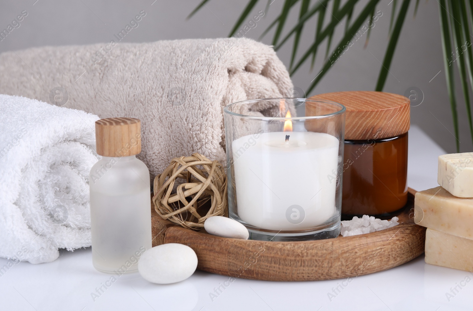 Photo of Composition with spa supplies on white table and palm leaf