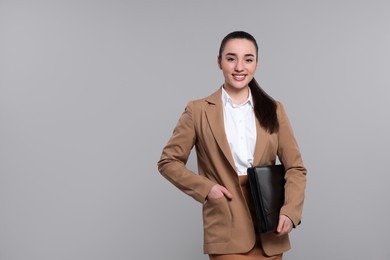Happy real estate agent with leather portfolio on grey background. Space for text
