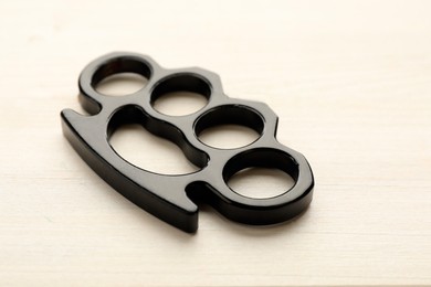 Photo of Black brass knuckles on white wooden background, closeup