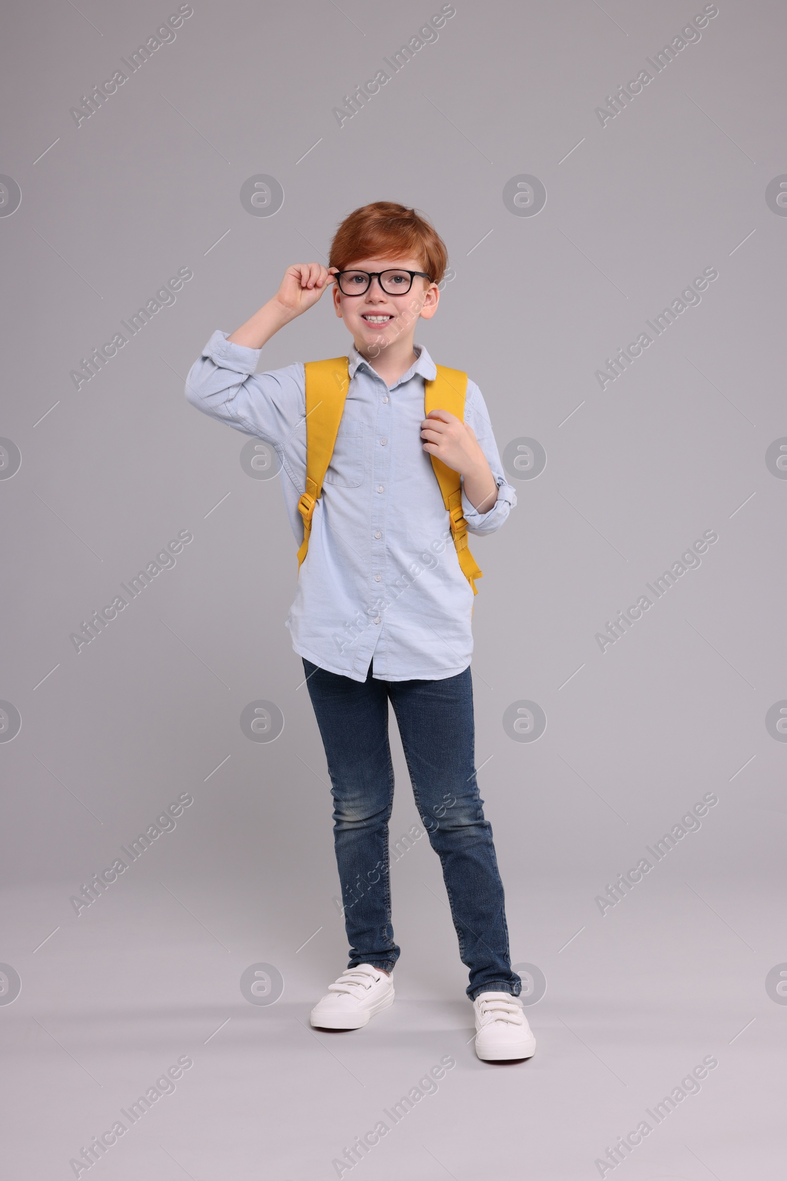 Photo of Happy schoolboy with backpack on grey background