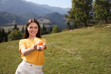 Photo of Happy woman with water gun having fun in mountains on sunny day