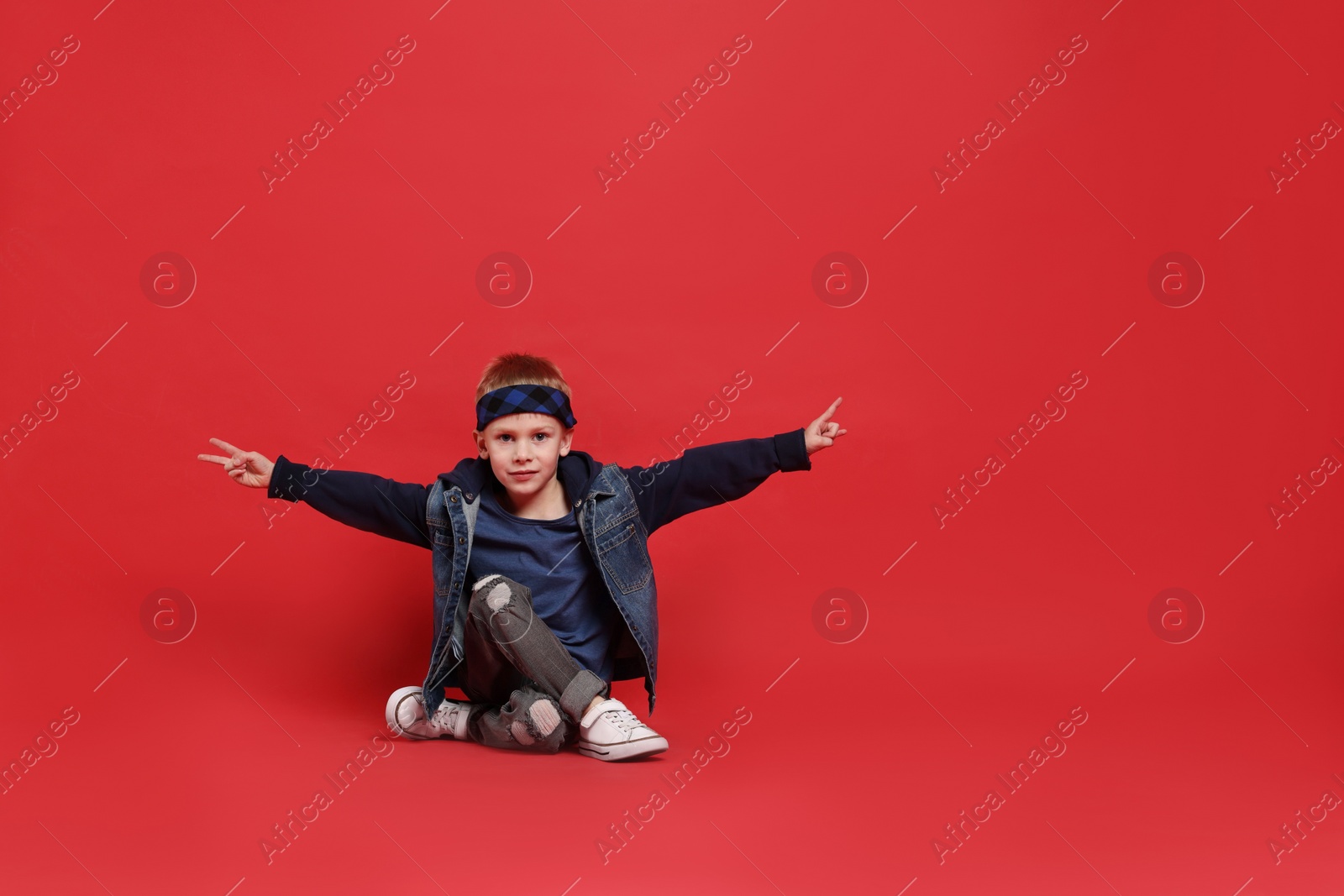 Photo of Happy little boy dancing on red background. Space for text