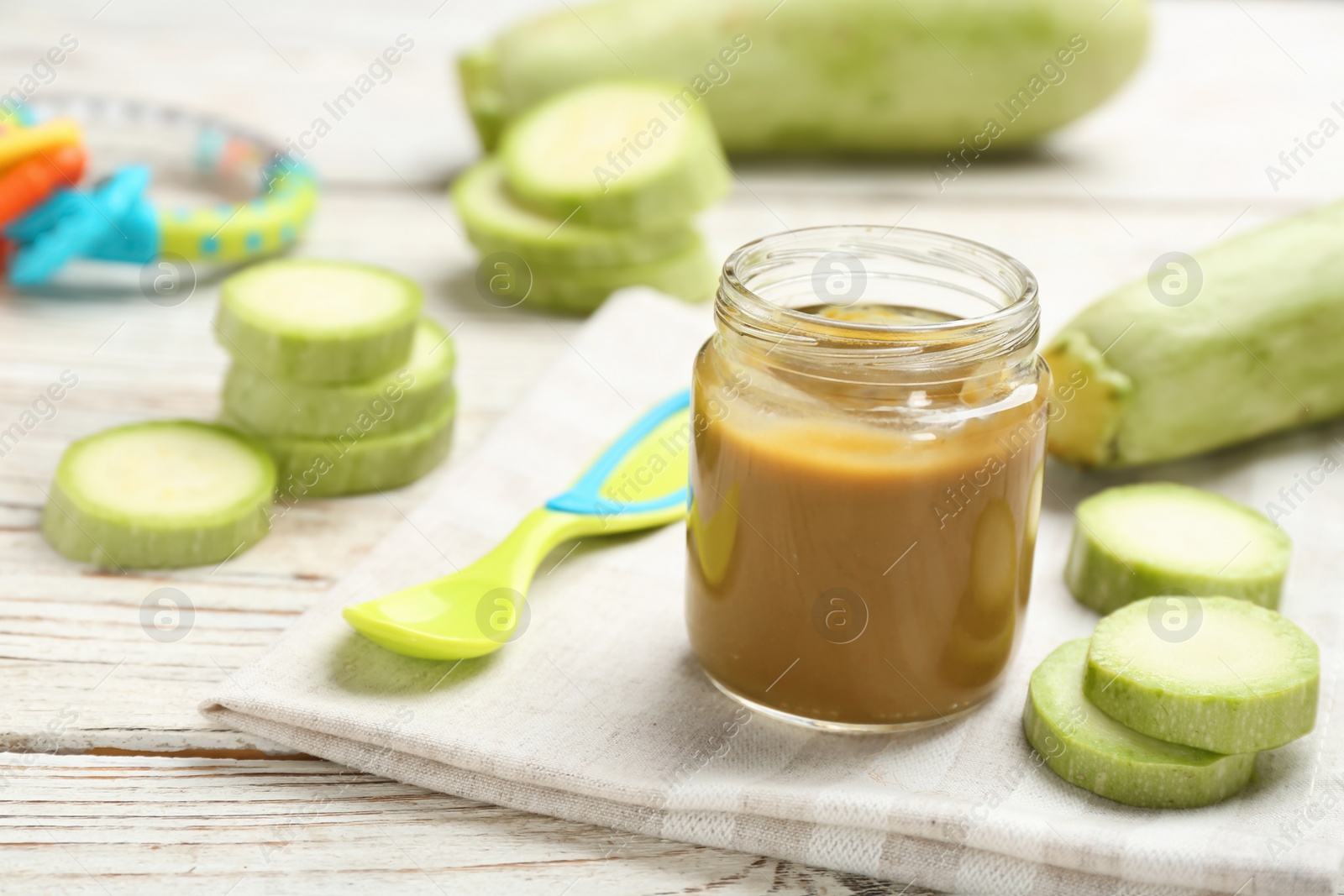 Photo of Jar with healthy baby food and zucchini on table