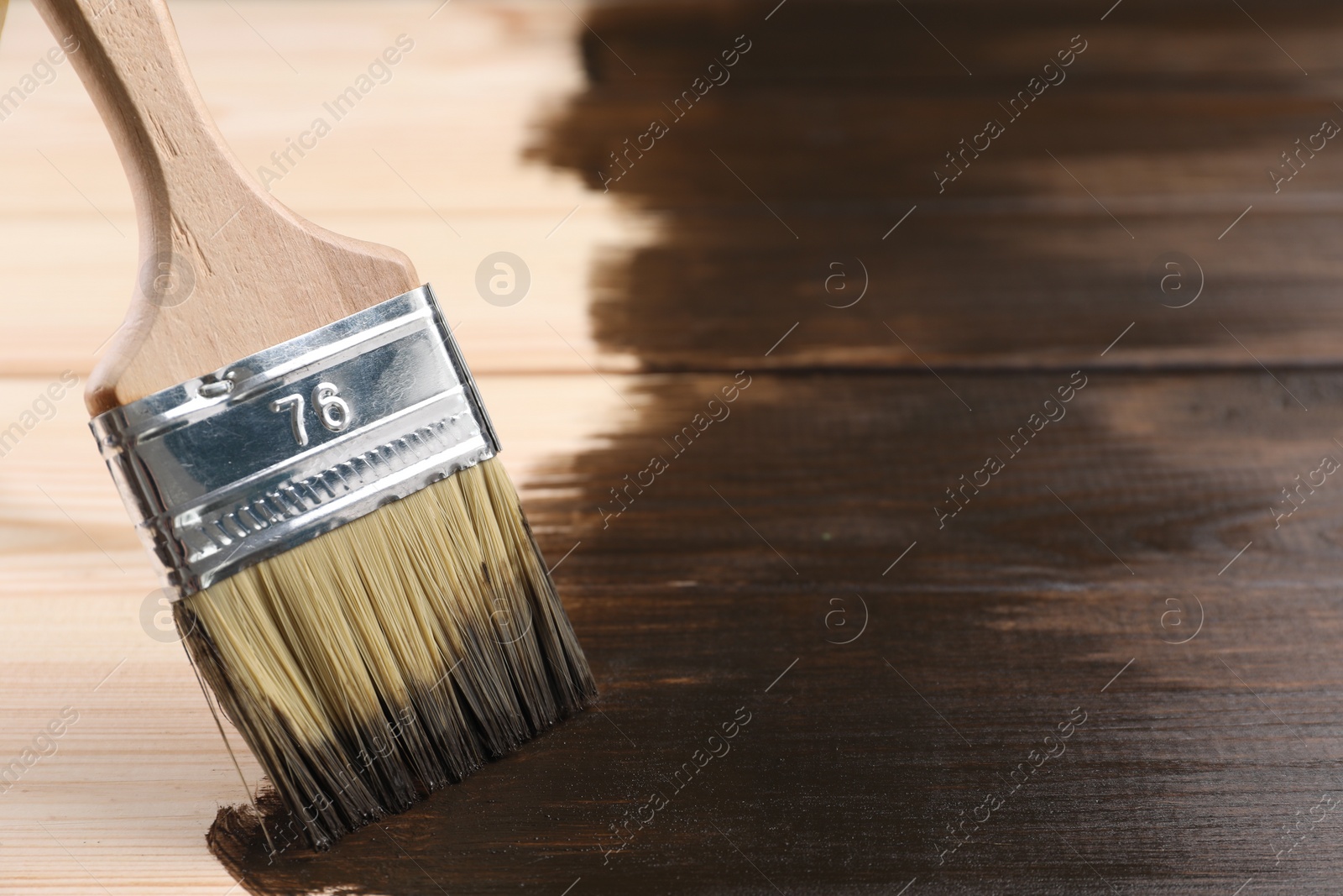 Photo of Applying wood stain with brush onto wooden surface, closeup. Space for text