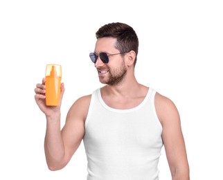 Handsome man in sunglasses holding bottle of sun protection cream on white background