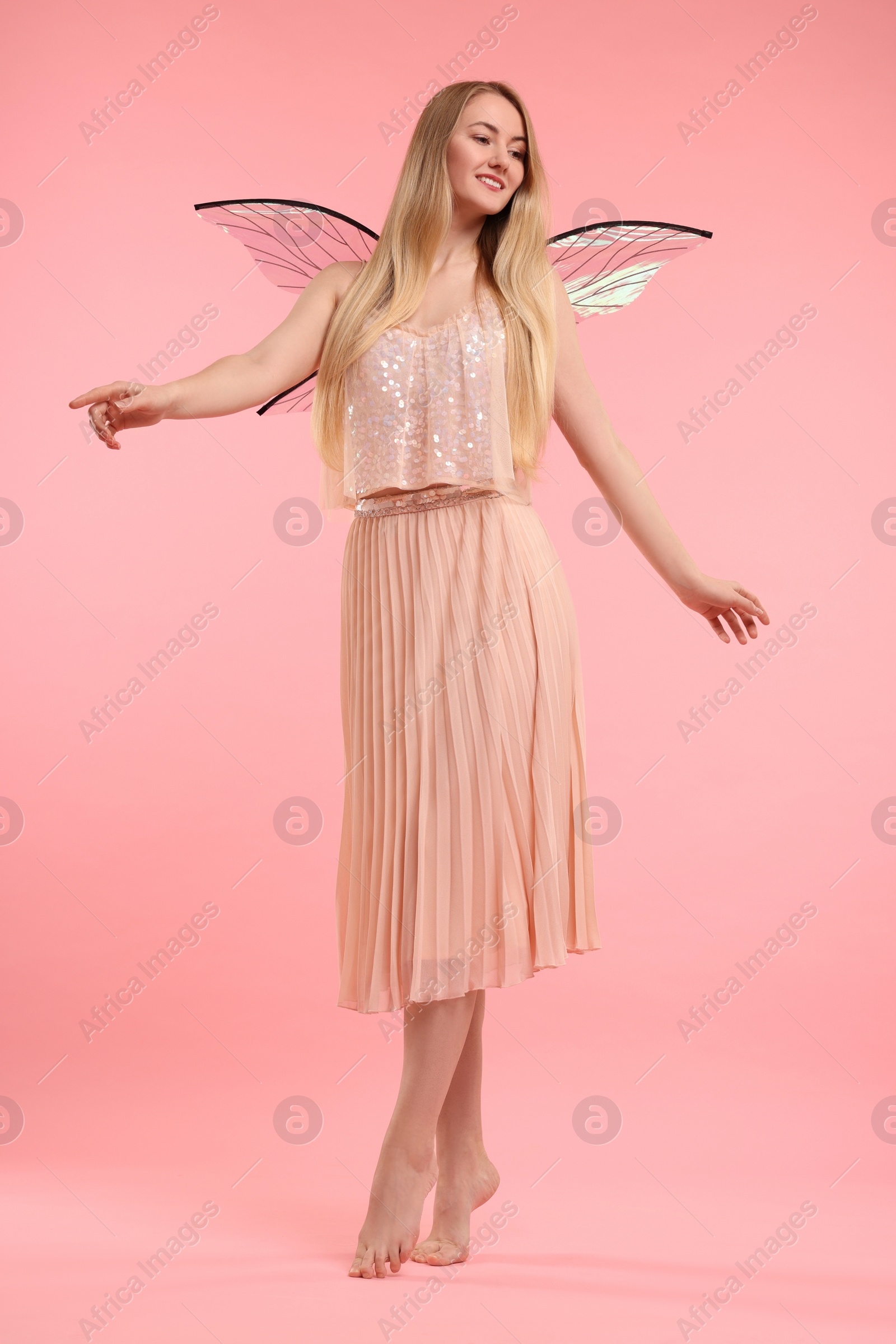 Photo of Beautiful girl in fairy costume with wings on pink background