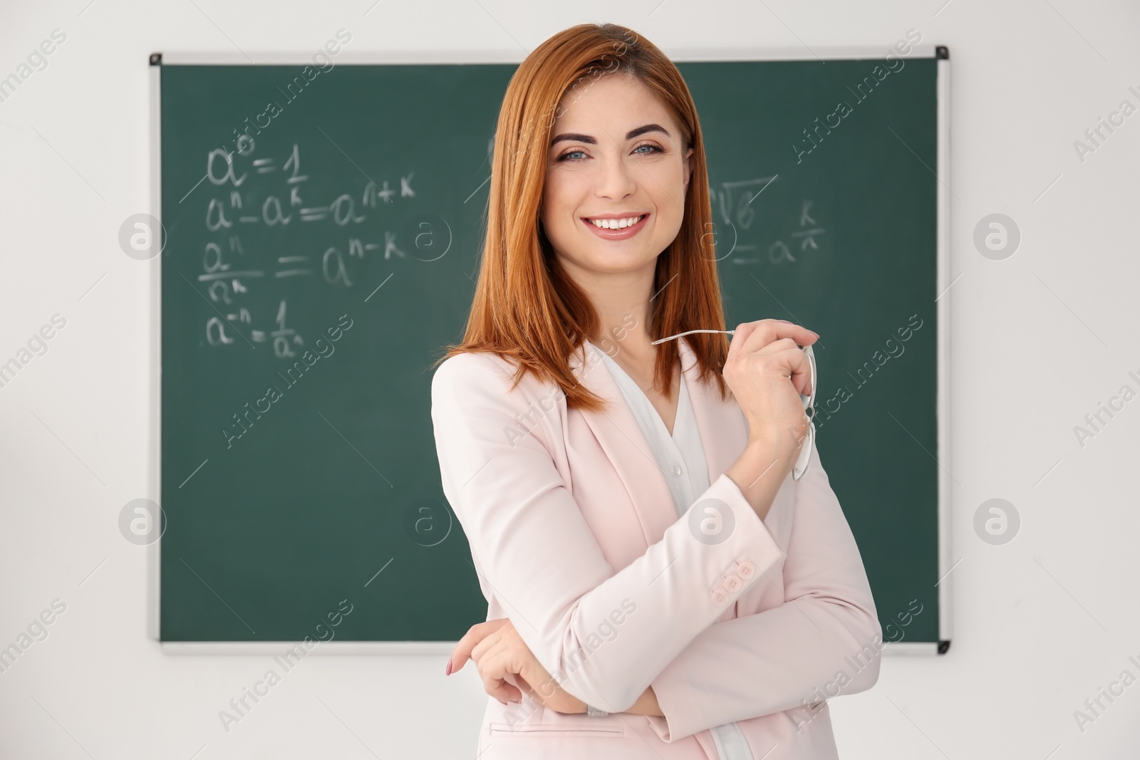 Photo of Beautiful young teacher near blackboard in classroom