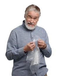 Photo of Emotional senior man popping bubble wrap on white background. Stress relief