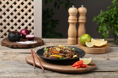 Photo of Stir-fry. Tasty noodles with meat and vegetables served on wooden table