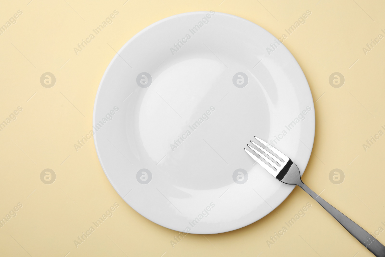 Photo of Empty plate and fork on color background, flat lay