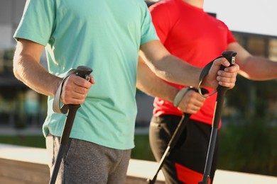 Photo of Men practicing Nordic walking with poles outdoors on sunny day, closeup