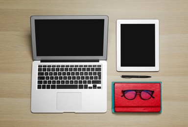 Modern gadgets, glasses and office stationery on wooden table, flat lay. Distance learning