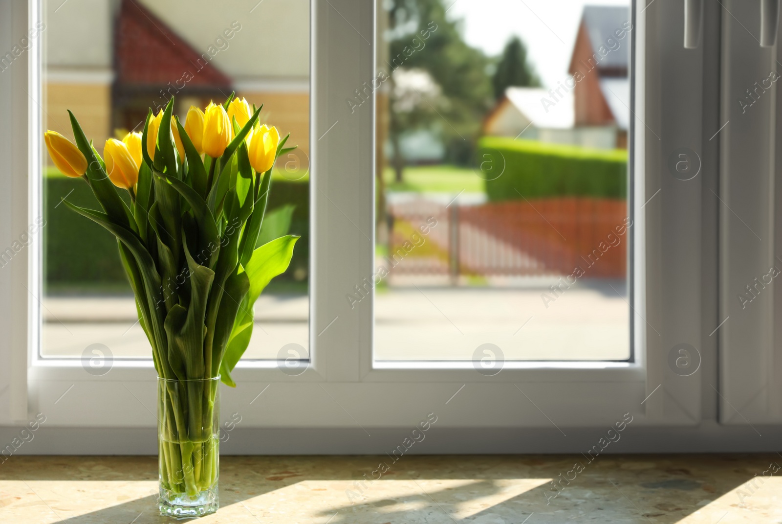 Photo of Bouquet of beautiful yellow tulip flowers in glass vase on windowsill. Space for text