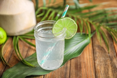 Jar with fresh coconut water and lime on wooden table