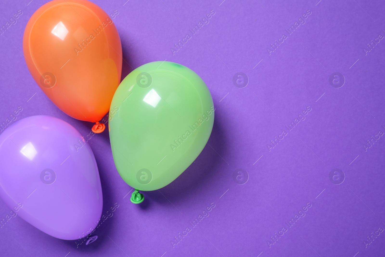 Photo of Colorful balloons on purple background, flat lay. Space for text