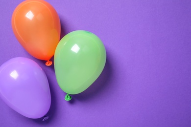 Photo of Colorful balloons on purple background, flat lay. Space for text