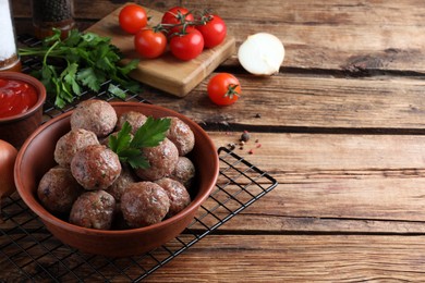 Tasty cooked meatballs with parsley on wooden table. Space for text