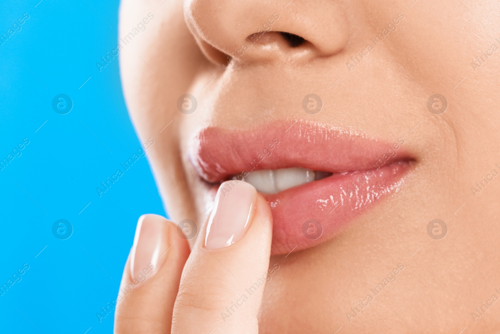 Photo of Young woman with beautiful full lips on light blue background, closeup