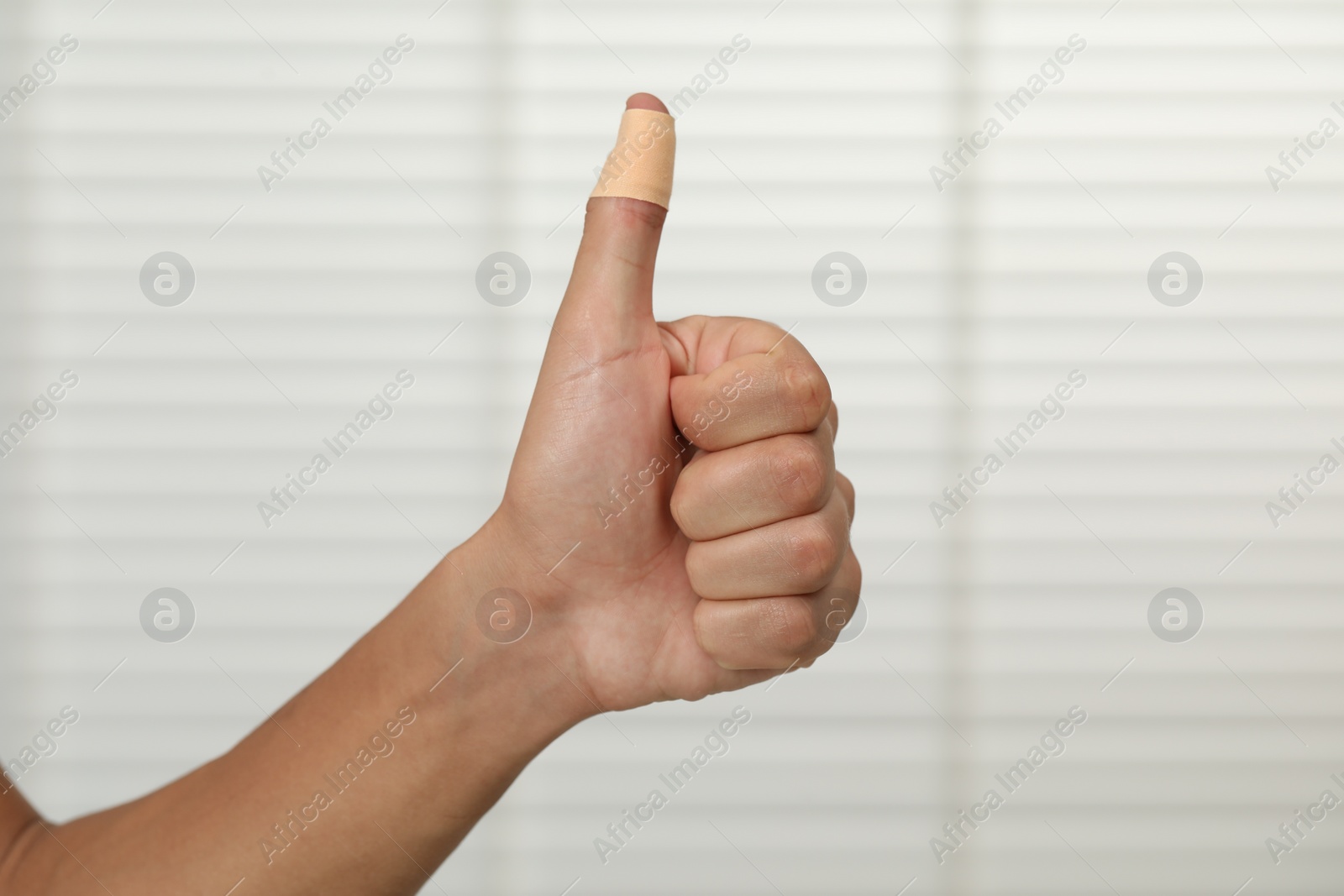 Photo of Man with sticking plaster showing thumb up indoors, closeup