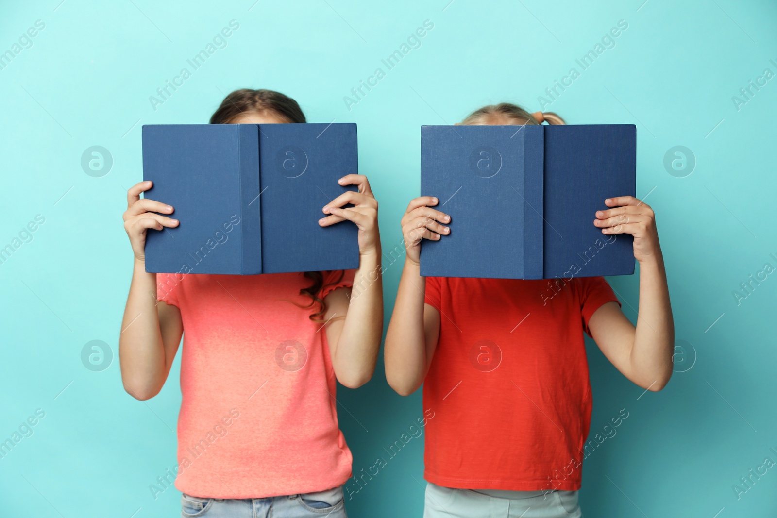 Photo of Little girls with books on turquoise background. Reading concept