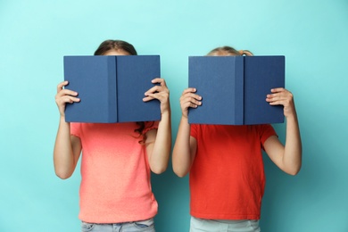 Little girls with books on turquoise background. Reading concept