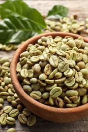 Photo of Green coffee beans and leaves on wooden table, closeup