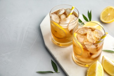 Glasses of lemonade with ice cubes and fruit on table. Space for text