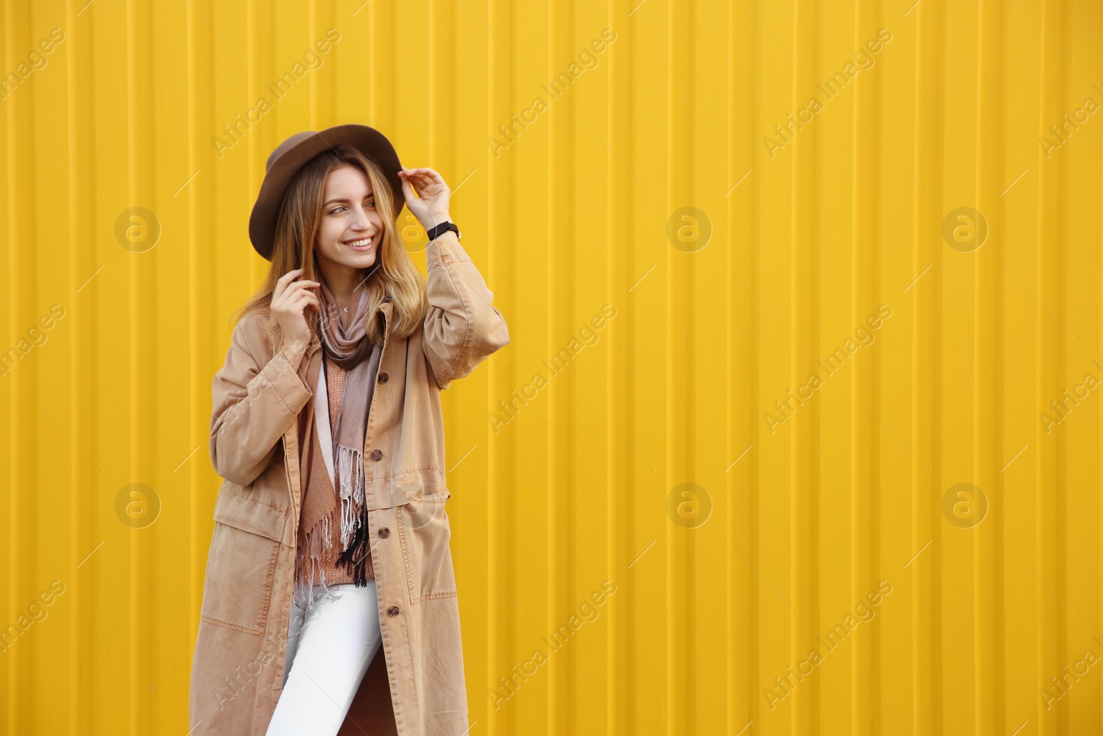 Photo of Beautiful young woman in stylish autumn clothes near yellow fence. Space for text