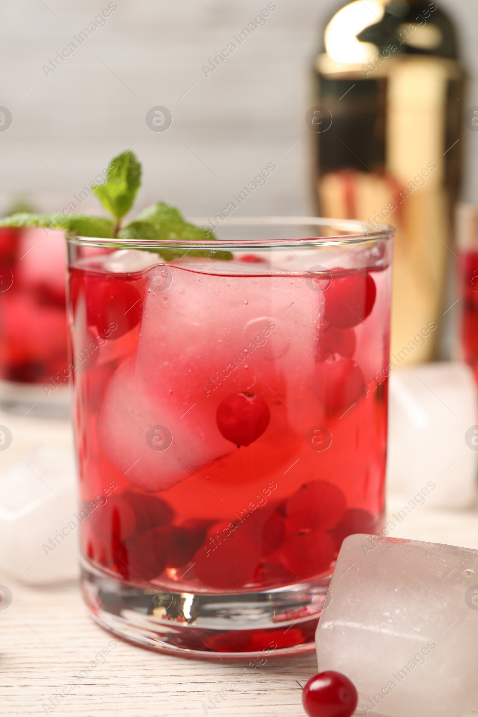 Photo of Tasty cranberry cocktail with ice cubes in glass on wooden table