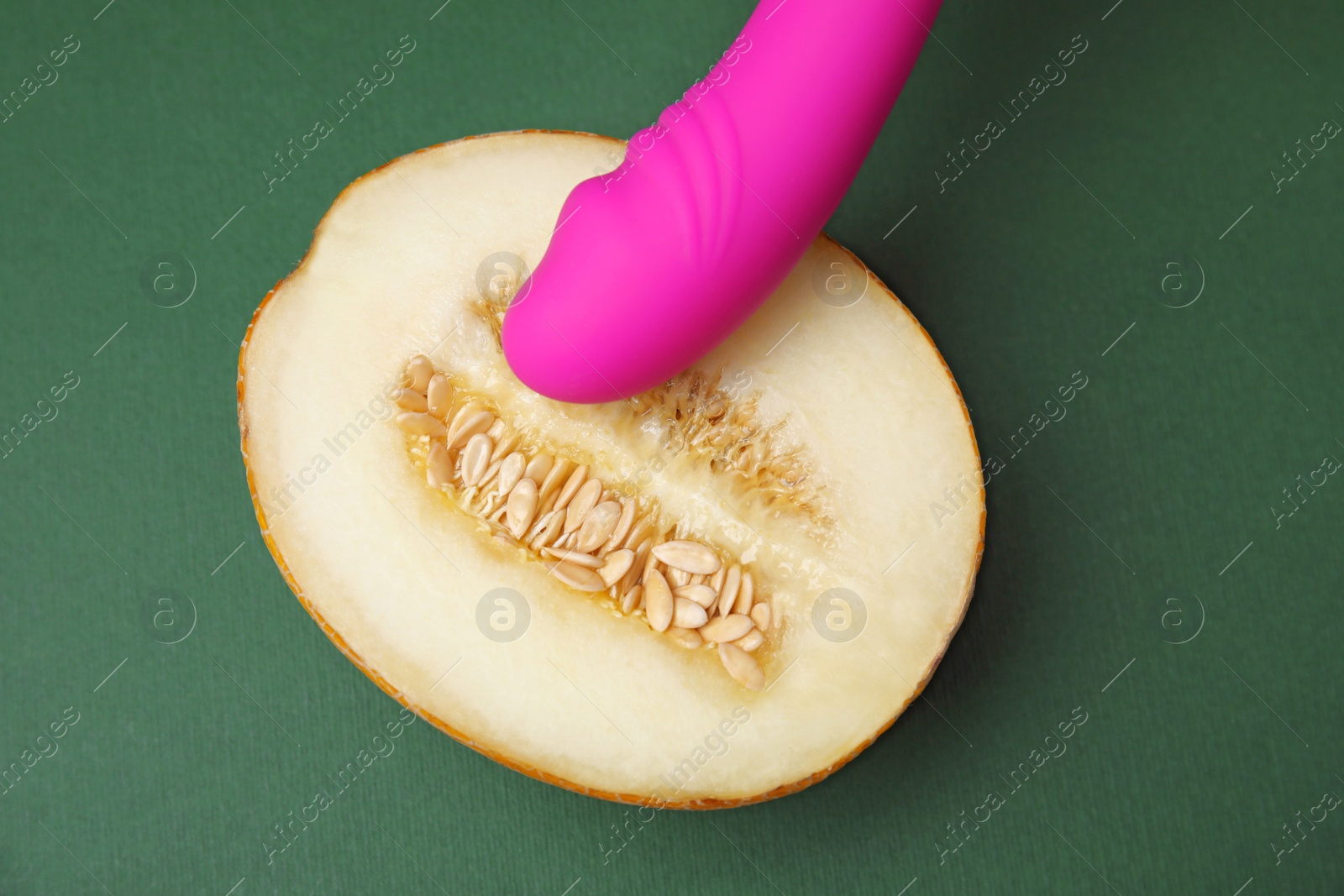 Photo of Half of melon and purple vibrator on dark grey background, flat lay. Sex concept