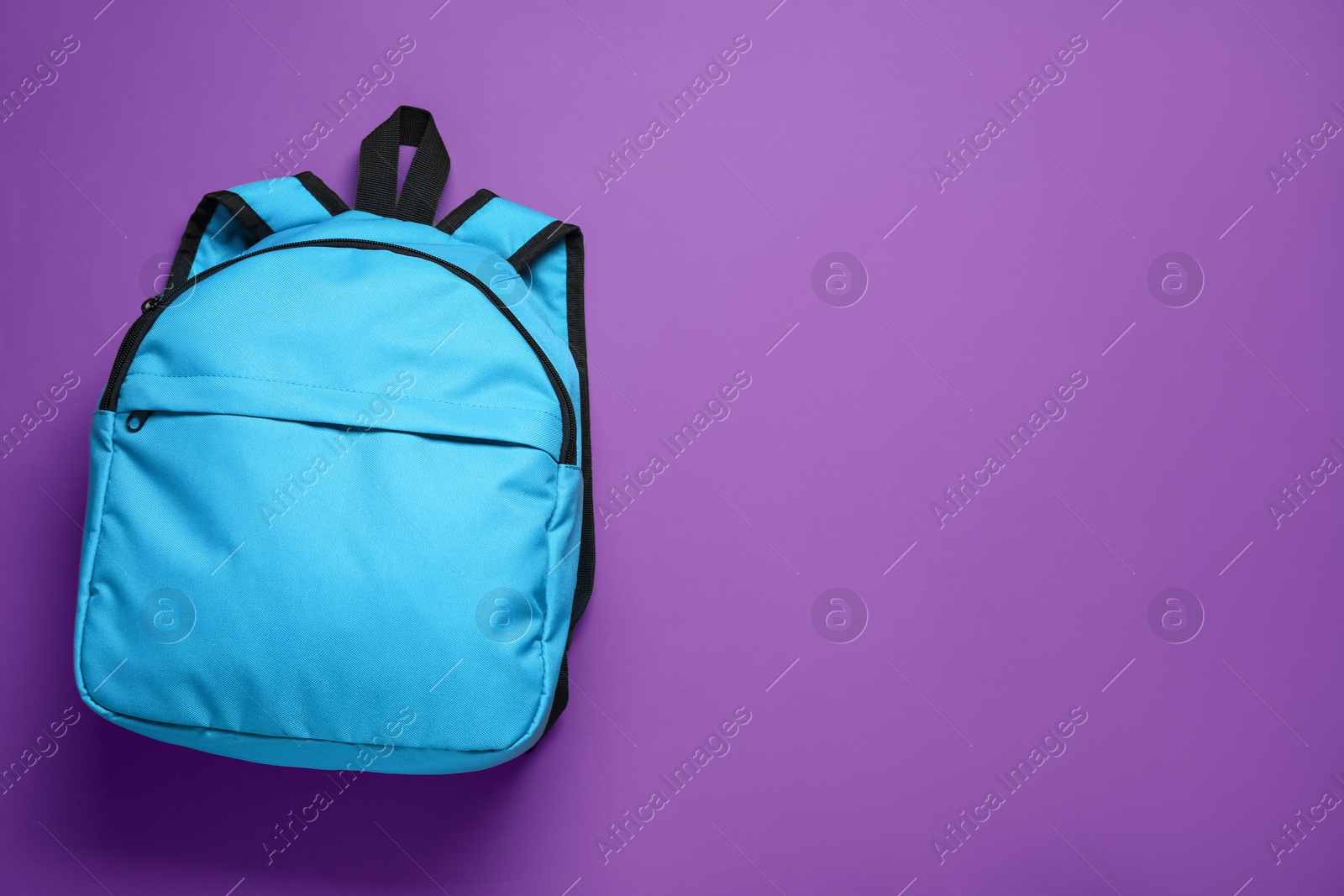 Photo of Stylish light blue backpack on purple background, top view. Space for text