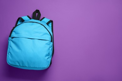 Stylish light blue backpack on purple background, top view. Space for text