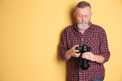 Photo of Mature male photographer with camera on color background