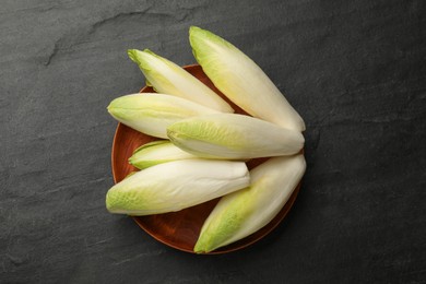 Photo of Fresh raw Belgian endives (chicory) on black table, top view