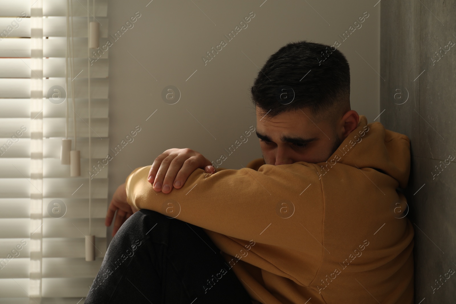 Photo of Sad man sitting near window at home
