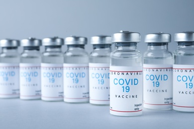 Photo of Vials with coronavirus vaccine on light grey background