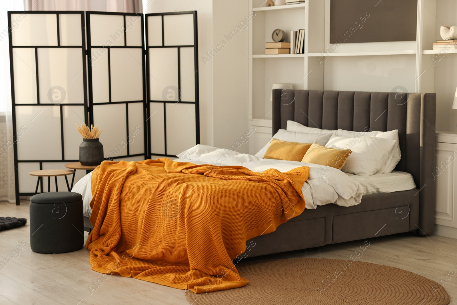 Photo of Bright plaid on bed in stylish bedroom. Interior design