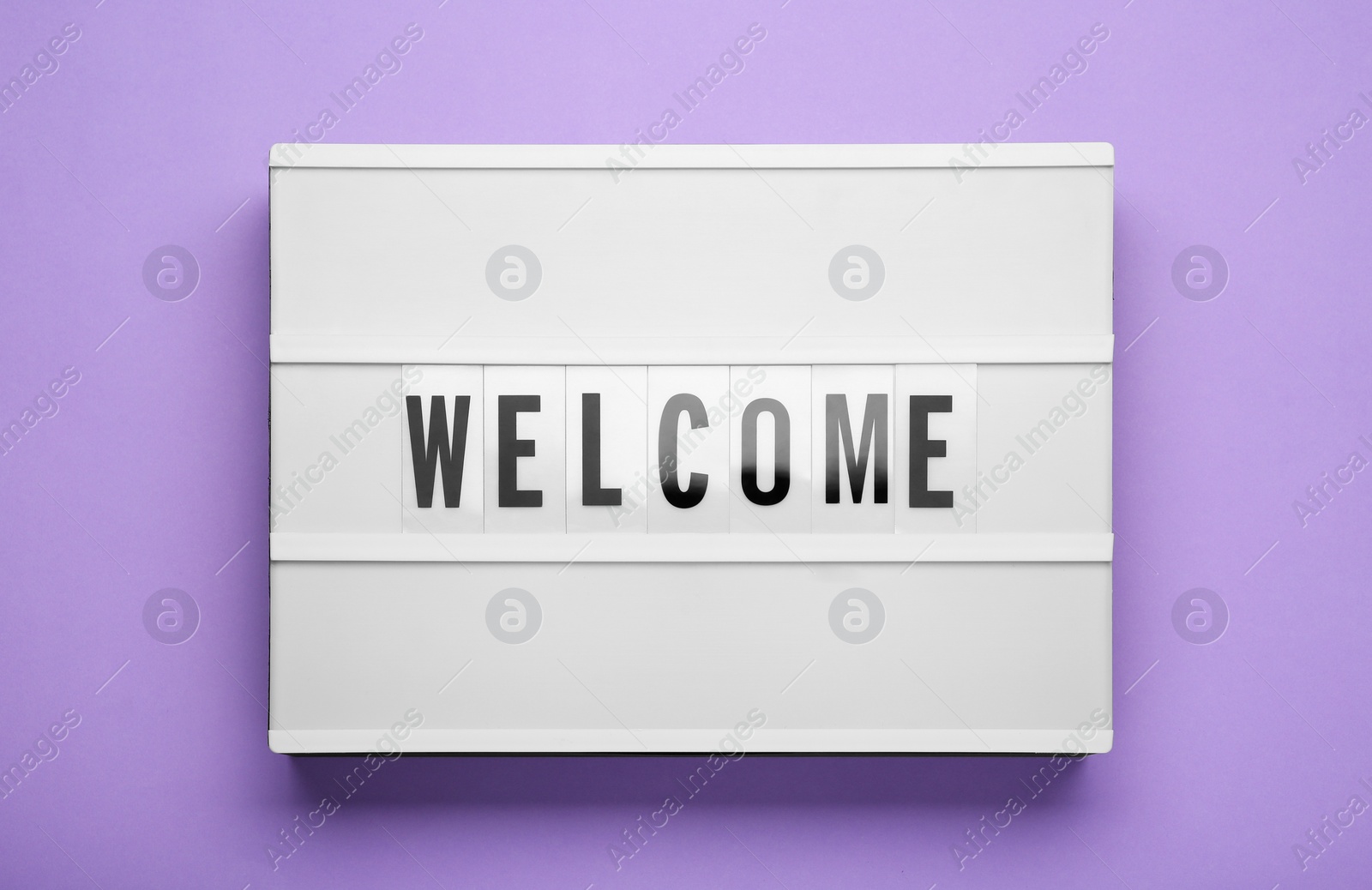 Photo of Lightbox with word Welcome on violet background, top view