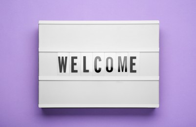 Lightbox with word Welcome on violet background, top view