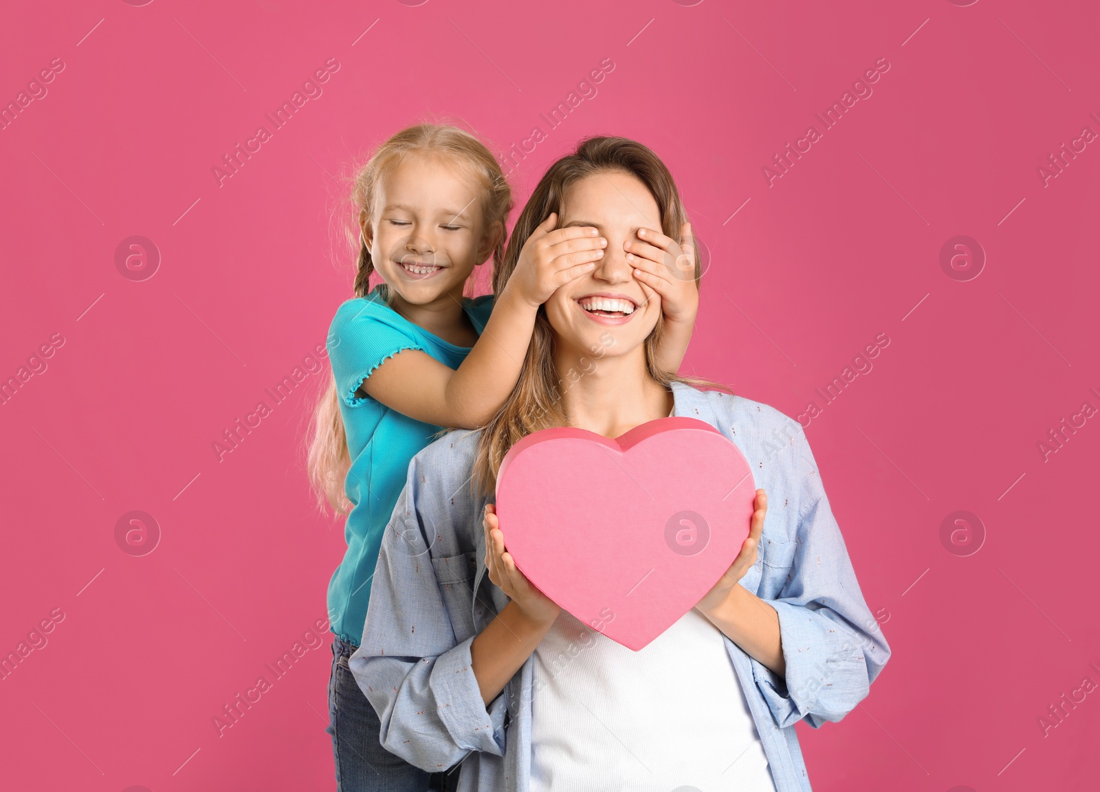 Photo of Little daughter congratulating her mom on pink background. Happy Mother's Day