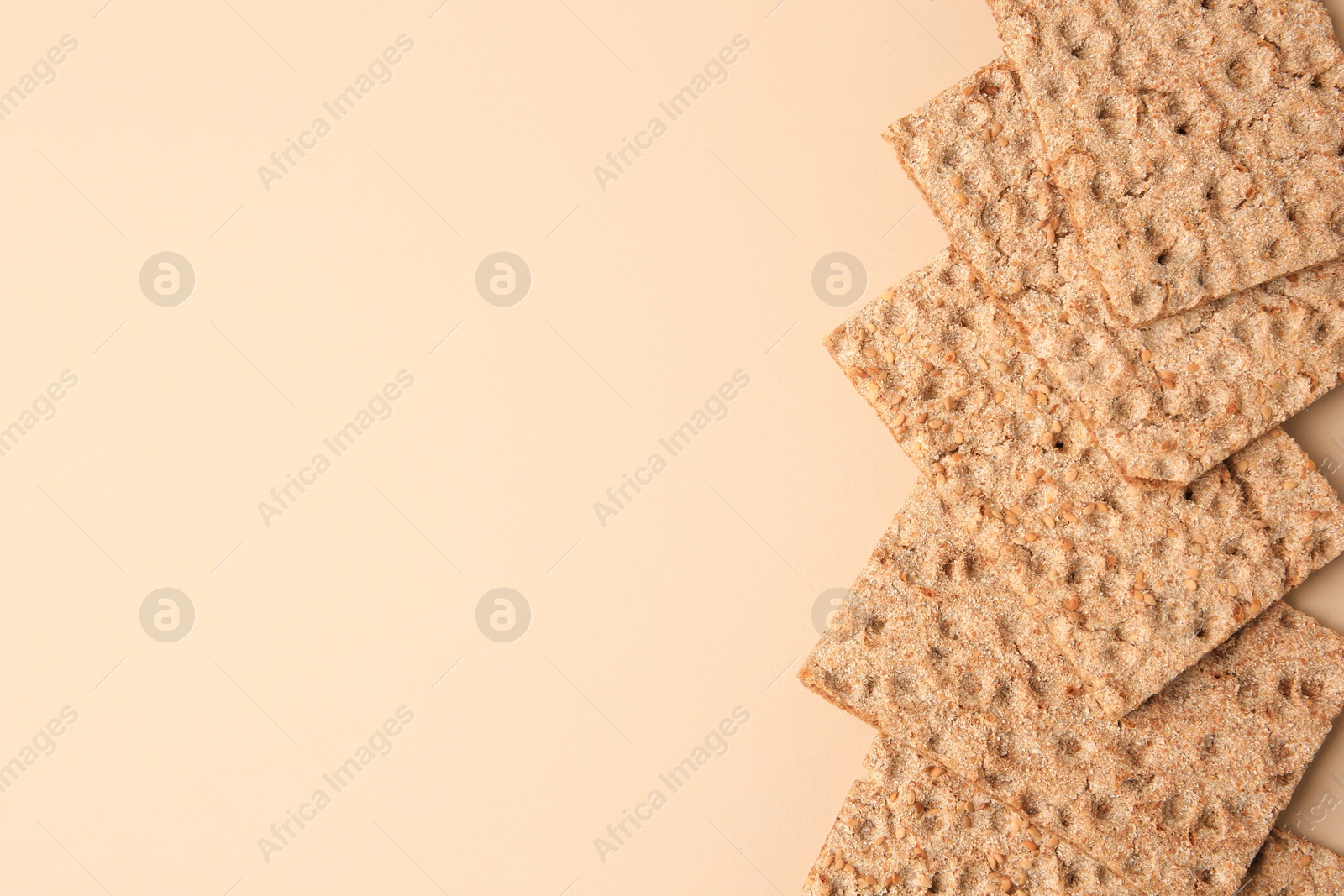 Photo of Fresh crunchy crispbreads on beige background, flat lay. Space for text